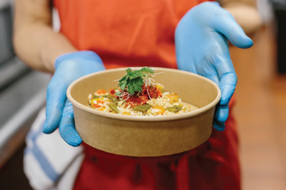 person presenting food in a fiber-based, compostable dish